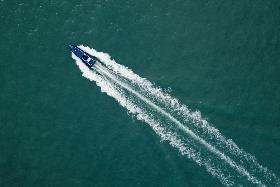 Aerial view of a blue motorboat and its wake on green water